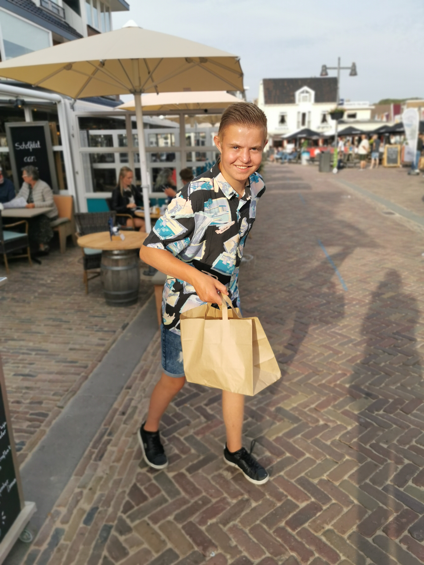 Blije klant met Vis aan Zee To Go tas op de boulevard in Egmond aan Zee